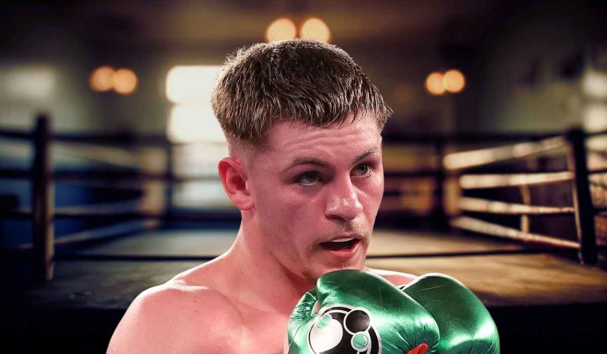 A boxer in the ring wearing green gloves, looking determined during a match
