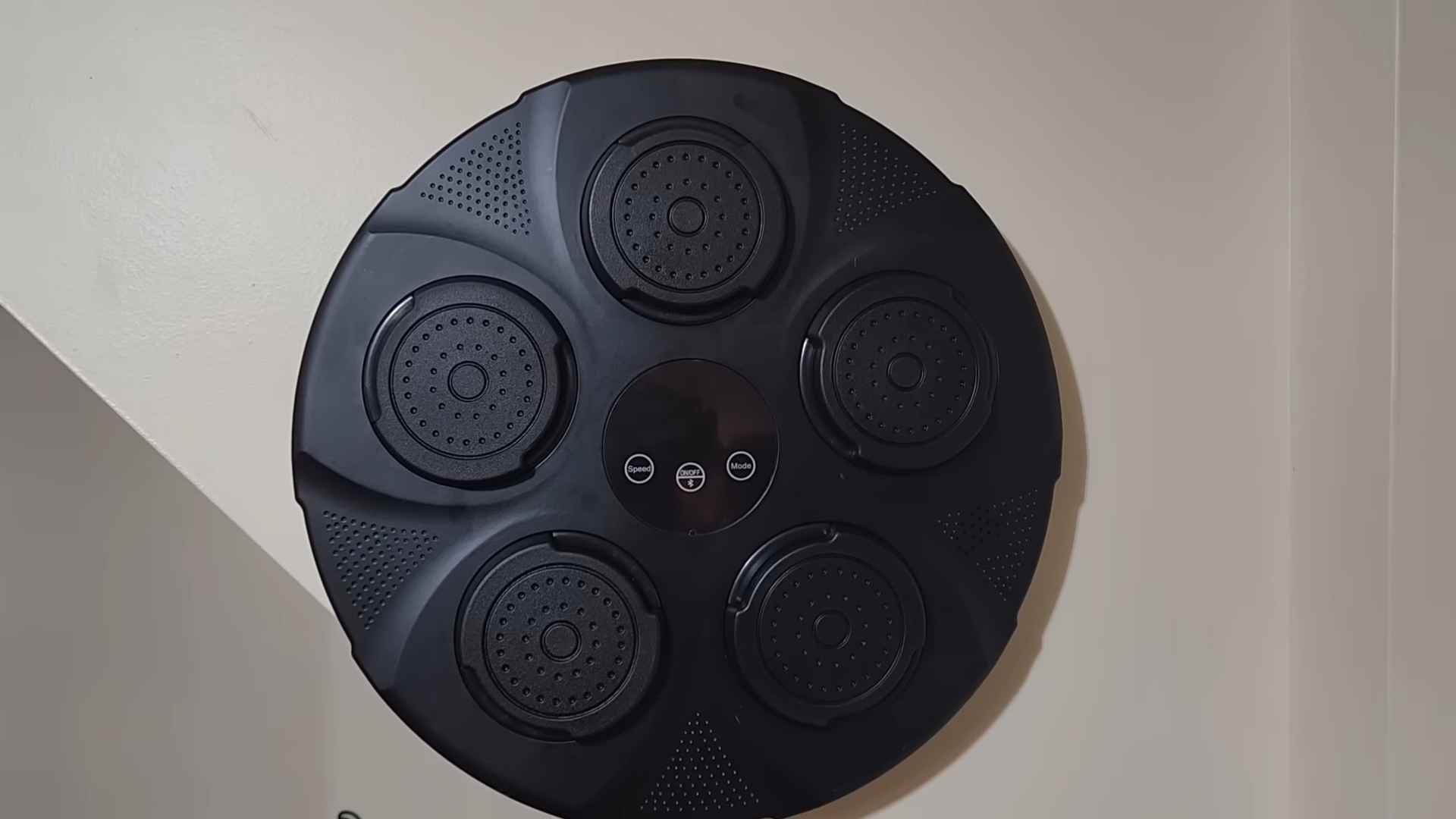 Round electronic boxing pad mounted on a wall with several circular target zones