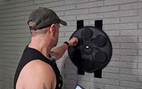 Man punching an electronic boxing pad mounted on a brick wall