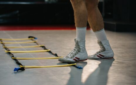 Boxing footwork drills with an agility ladder as a beginner practices quick, controlled steps on a gym floor