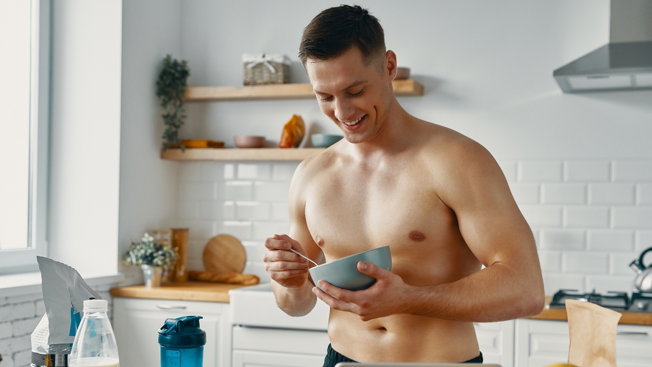 Man eating a pre boxing meal in the kitchen with protein powder and shaker nearby